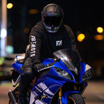 Person on a blue motorcycle wearing a black helmet with reflective visor at night.