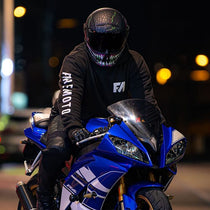 Person on a blue motorcycle wearing a black helmet with reflective visor at night.